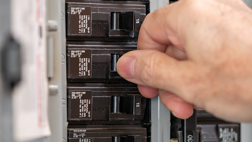 Close-up of electrician checking electrical panel breakers in Pasco County